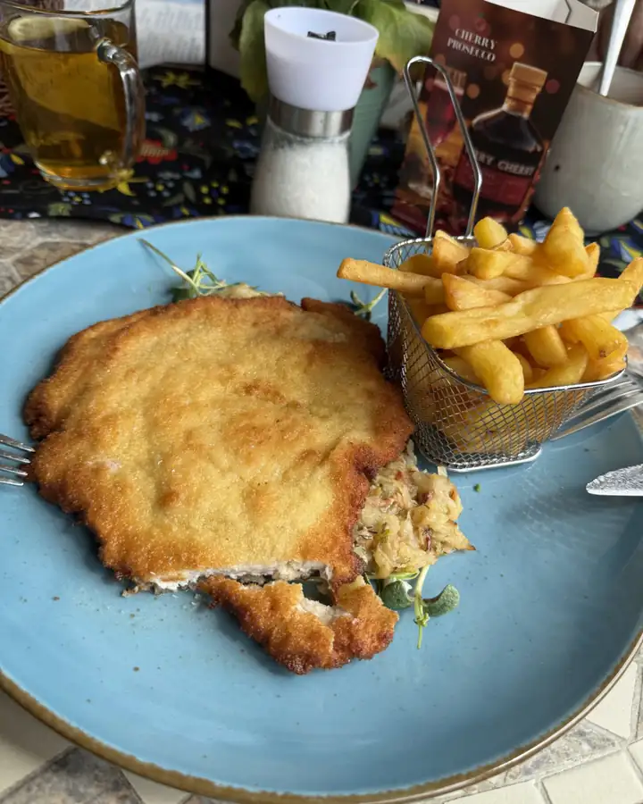 Kotlet schabowy z frytkami i surówką na niebieskim talerzu